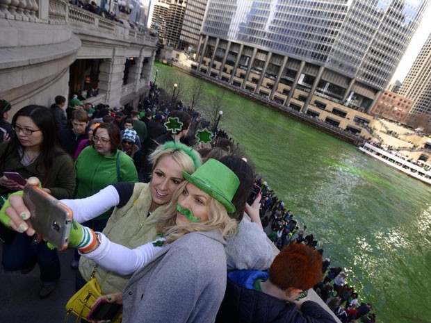 Espectadoras olham para o Chicago River, nos EUA também pintado de verde para o Dia de São Patrício (Foto: Paul Beaty/AP)