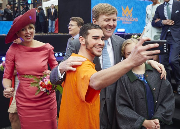 Holandês tira selfie com o rei do país Willem-Alexander durante o Dia do Rei; de rosa, a rainha Máxima (Foto: Phil Nijhuis/AP)