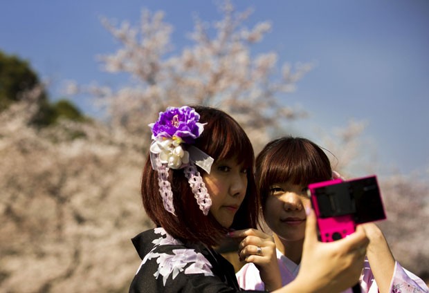 Japonesas no parque Ueno, em Tóquio, admiram a floração plena das cerejeiras no dia 30/3 (Foto: Thomas Peter/Reuters)