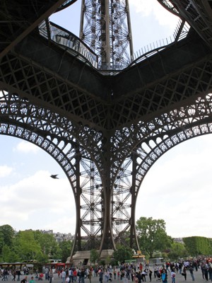 Turistas andam embaixo da Torre Eiffel nesta sexta-feira (22), em Paris (Foto: Remy de la Mauviniere/AP)
