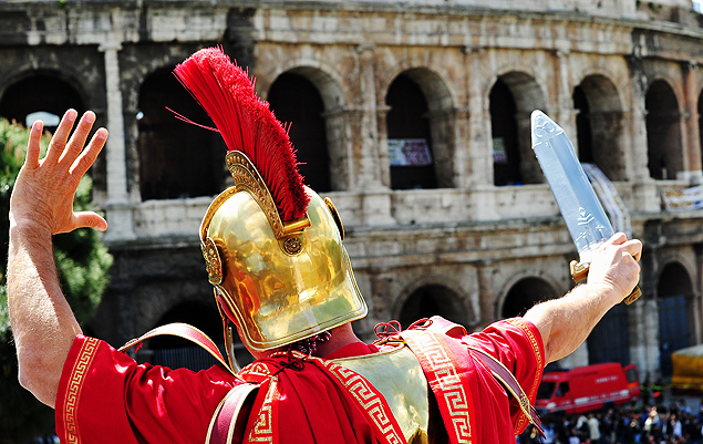 (FILES) - A man dressed as a Roman centurion and who earn his living by posing with tourists gestures in front of the Colosseum during a protest on April 12, 2012 in Rome. Rome Commissioner Francesco Paolo Tronca banned the costumed centurions from posing for photographs with tourists for a fee on November 26, 2015 ahead of the Pope's Jubilee. Rickshaws who offered tourists an alternative to horse-drawn buggies were seized in the interests of urban security and decorum, city sources said. The ban is imposed in the interests of security - in so far as the people performing such activities often behave in ways that are inappropriate, insistent and sometimes aggressive - and to protect the decency of the city's artistic, historic and monumental heritage, Tronca's ordinance read. AFP PHOTO / ALBERTO PIZZOLI ORG XMIT: APZ330