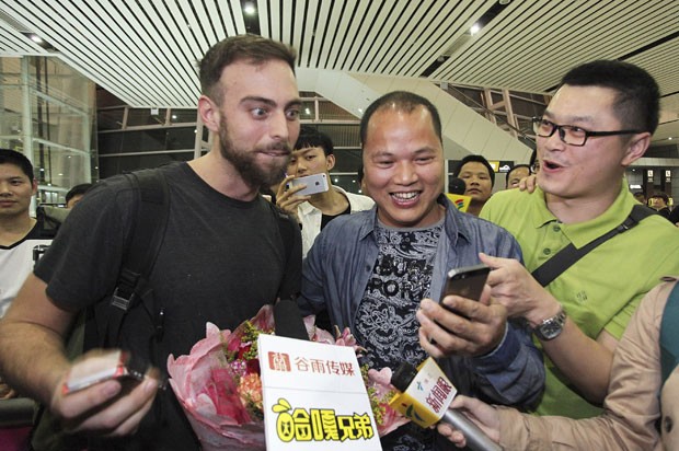 Matt Stopera é recebido pelo 'irmão laranja' no aeroporto da China (Foto: Reuters)