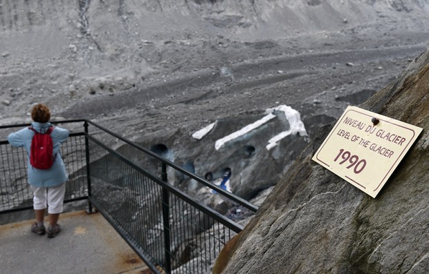 Visitante olha para caverna do Mar de Gelo; placa indica nível da geleira em 1990 (Foto: AFP Photo/Philippe Desmazes)