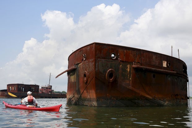 Turista se aproxima de embarcação deteriorada em estaleiro em Nova York, durante tour por ‘cemitério de navios’ (Foto: Shannon Stapleton/Reuters)