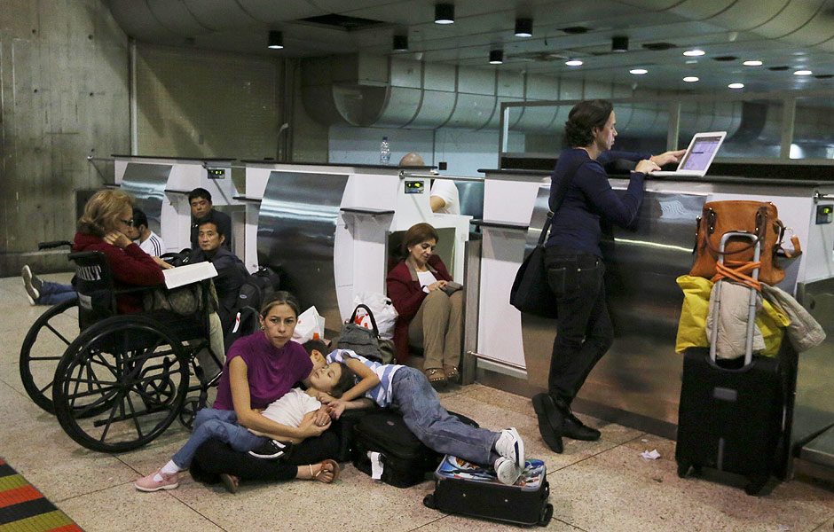 Passengers lie on the ground after their Air France flight 385 to Paris was called at Simon Bolivar Airport in Maiquetia near Caracas, Venezuela, Sunday, Dec. 15, 2013. Venezuelan bomb experts are inspecting a grounded Air France flight after being tipped off by French authorities that a terrorist group may be planning to detonate an explosive device in midair. Venezuelan Interior Minister Miguel Rodriguez Torres told state TV that a team of more than 60 technicians are performing an exhaustive search of the aircraft that will take several hours before the flight can be rescheduled. (AP Photo/Fernando Llano) ORG XMIT: XFLL101