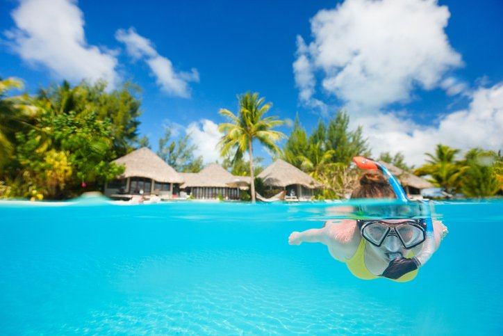 Woman snorkeling in clear tropical waters in front of exotic island