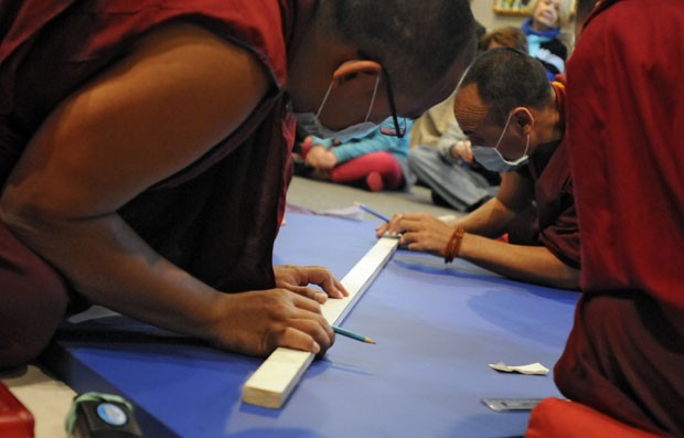 Monges traçam linhas da mandala que será preenchida com areia colorida (Foto: AP Photo/The Sun News, Charles Slate)