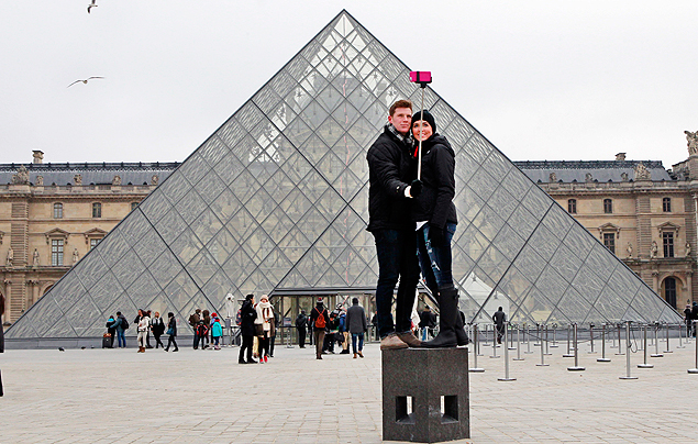 Turistas usam 'pau de selfie' para tirar fotografia em frente ao museu do Louvre, em Paris