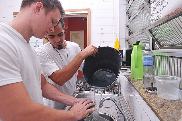 Turista e funcionrio do Vila Madalena Hostel lavam loua com gua do banheiro