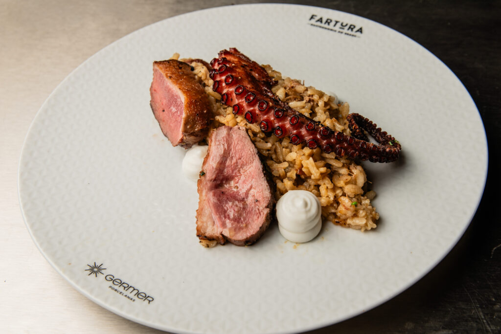 A chef Jana Barrozo, dos restaurantes Cabernet Butiquim, Rex Bibendi e Adeguinha (Belo Horizonte, MG), cozinha ao vivo polvo e camarão em pedaços, pururuca de pé de porco, servidos com aioli pimentão defumado. Crédito: Fabrício Guedes