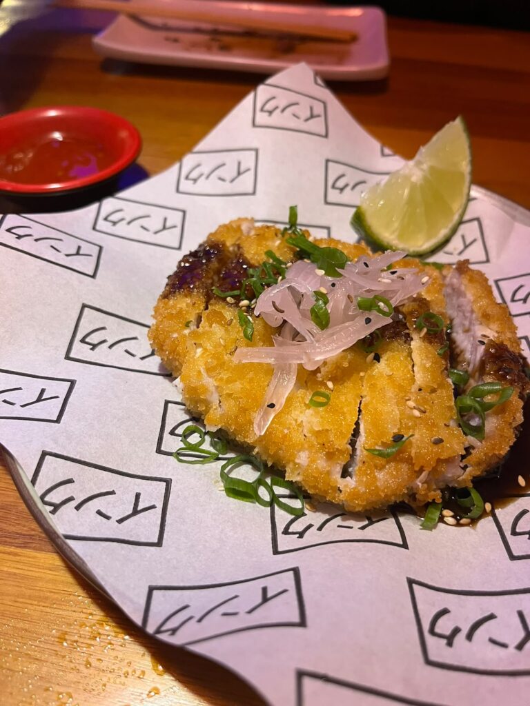 Tonkatsu (Porco empanado com farinha panko e frito, finalizado com molho tonkatsu, cebola roxa e cebolinha. Acompanhados de molho da casa - maionese levemente apimentada). Crédito: Arquivo Pessoal