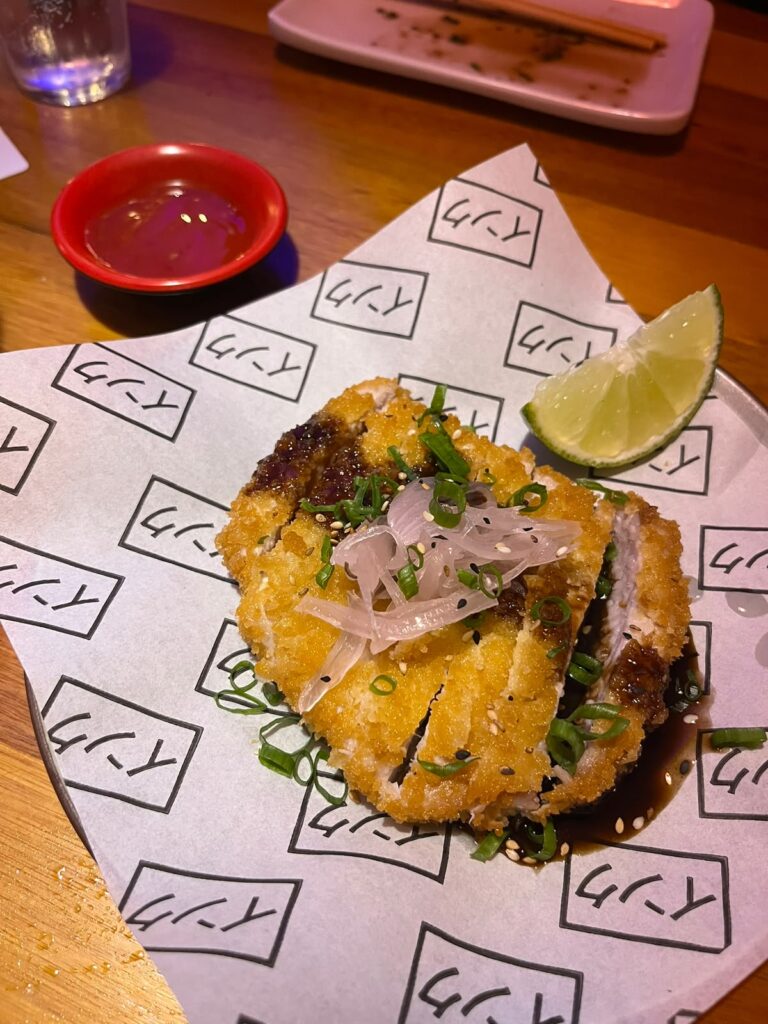 Tonkatsu (Porco empanado com farinha panko e frito, finalizado com molho tonkatsu, cebola roxa e cebolinha. Acompanhados de molho da casa - maionese levemente apimentada). Crédito: Arquivo Pessoal
